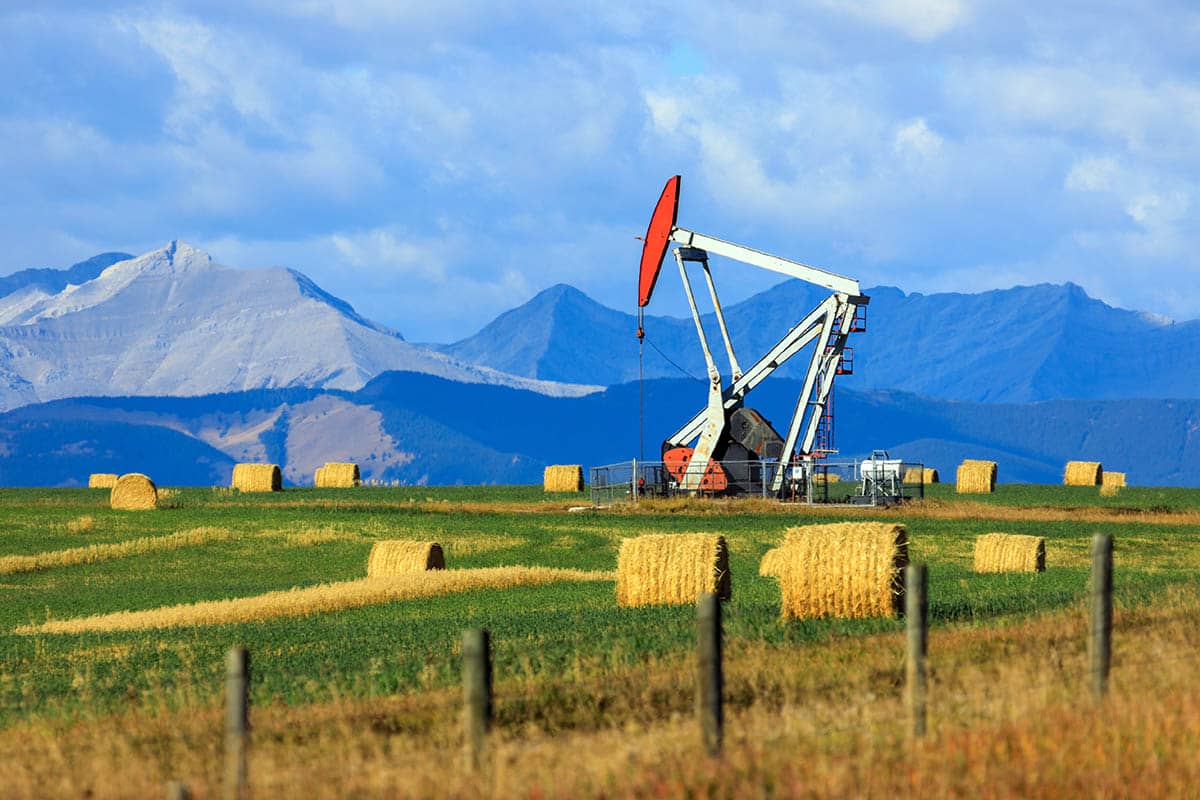 oil well in farm field with hay bails