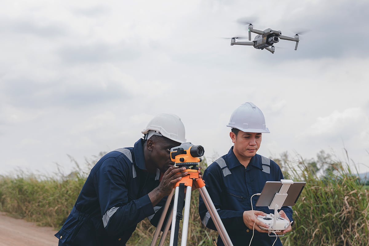 Workers collecting data from a drone and survey equipment